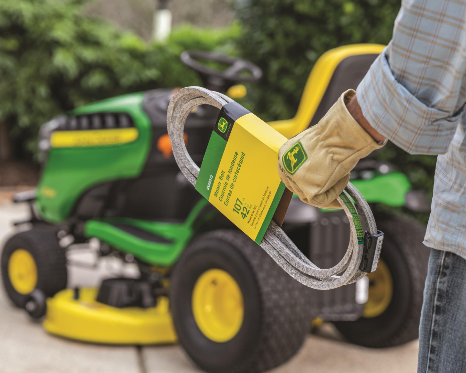 A worker changes a mower belt on a John Deere lawn tractor.