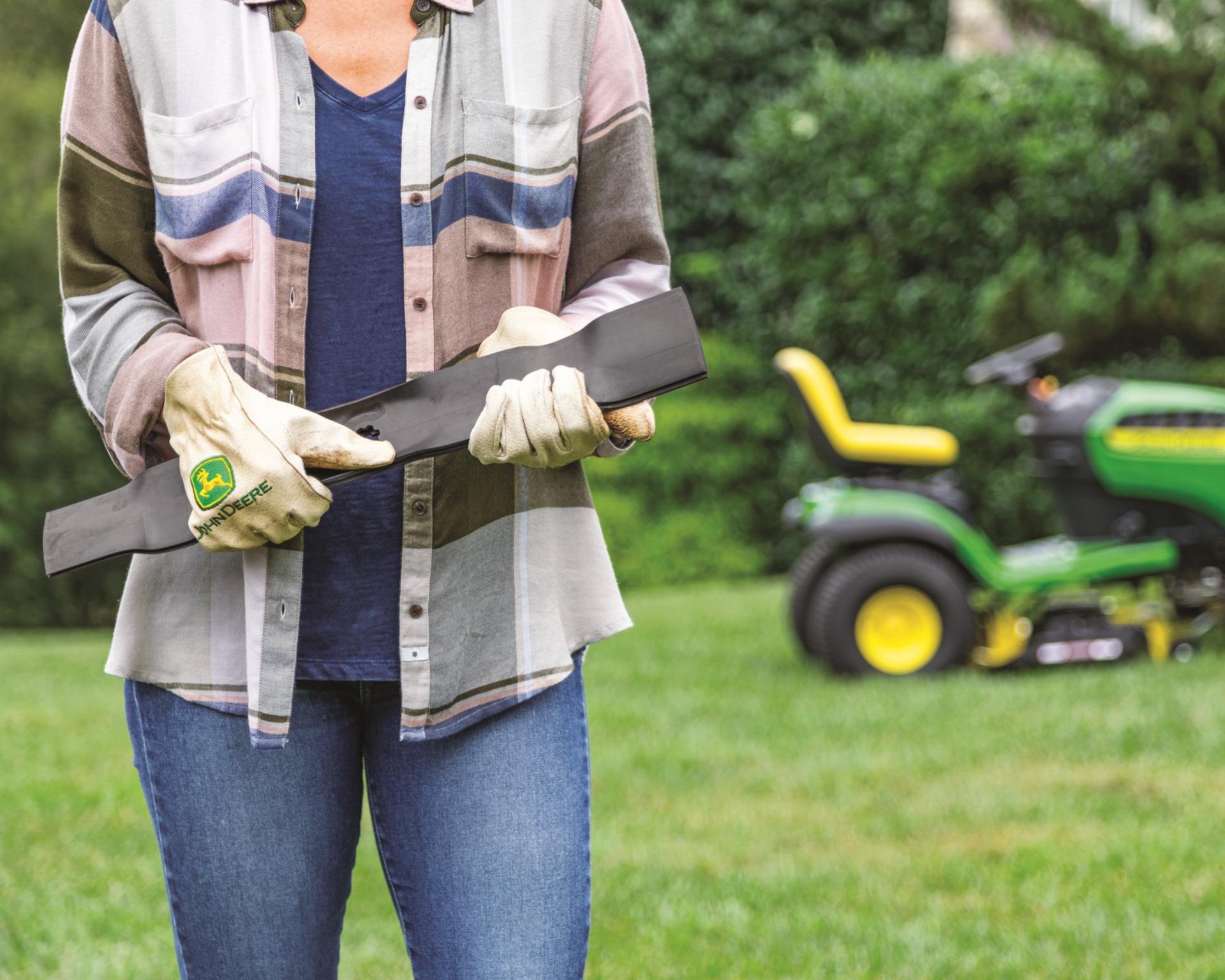 A person changes mower blades on their John Deere lawn tractor.