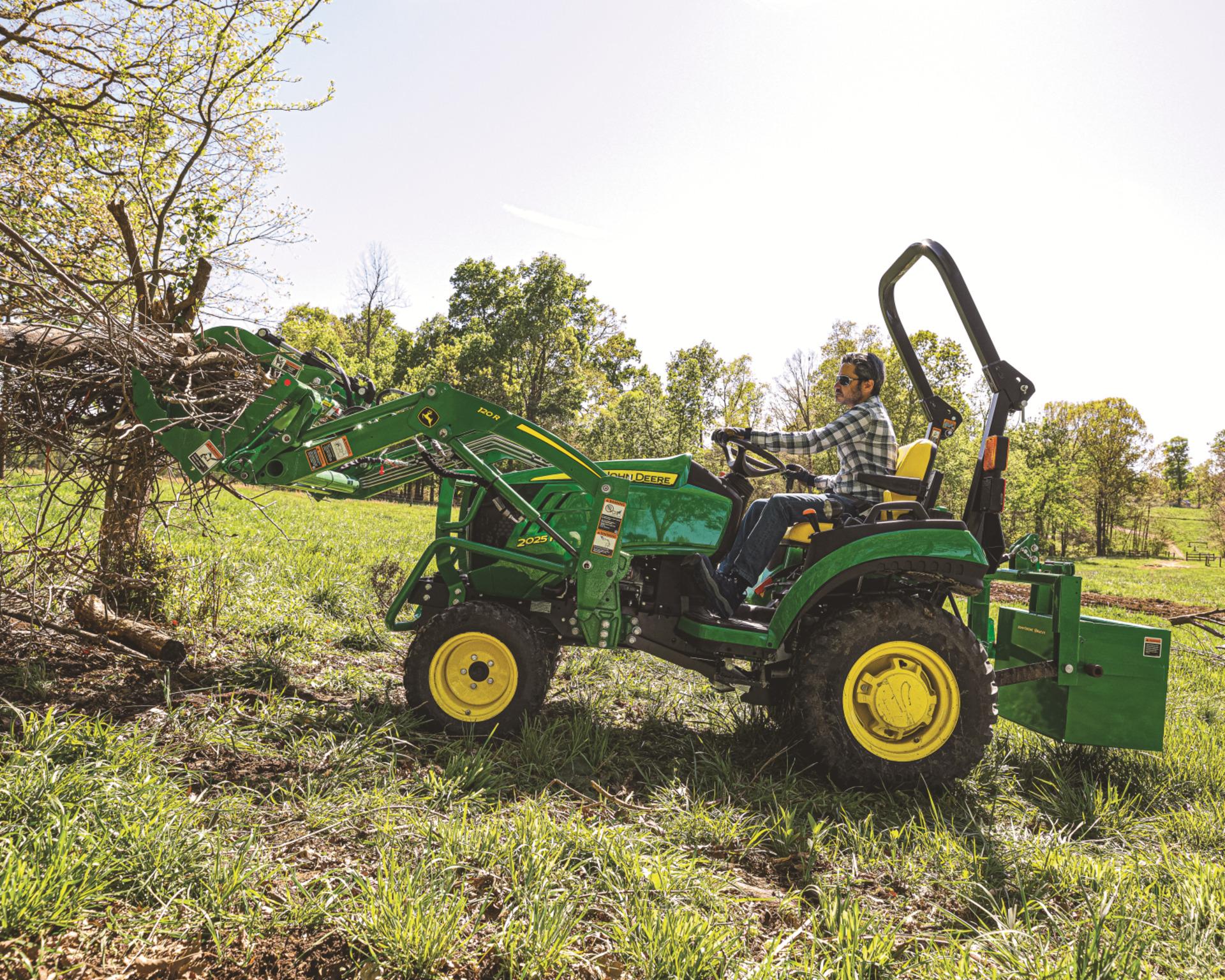 John Deere 2025R lifting debris on a property.