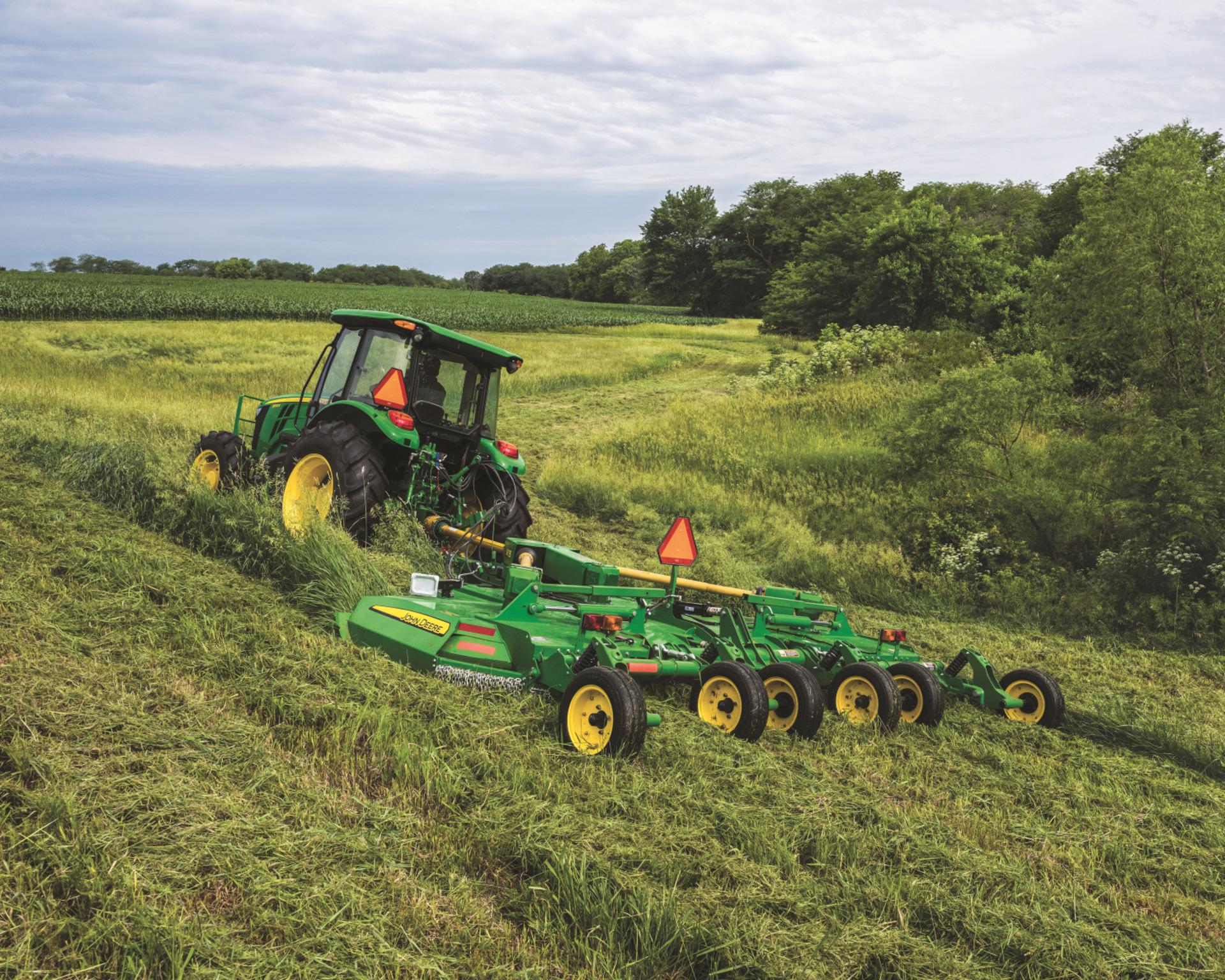 A John Deere tractor uses AutoTrac with a rotary cutter attachment.