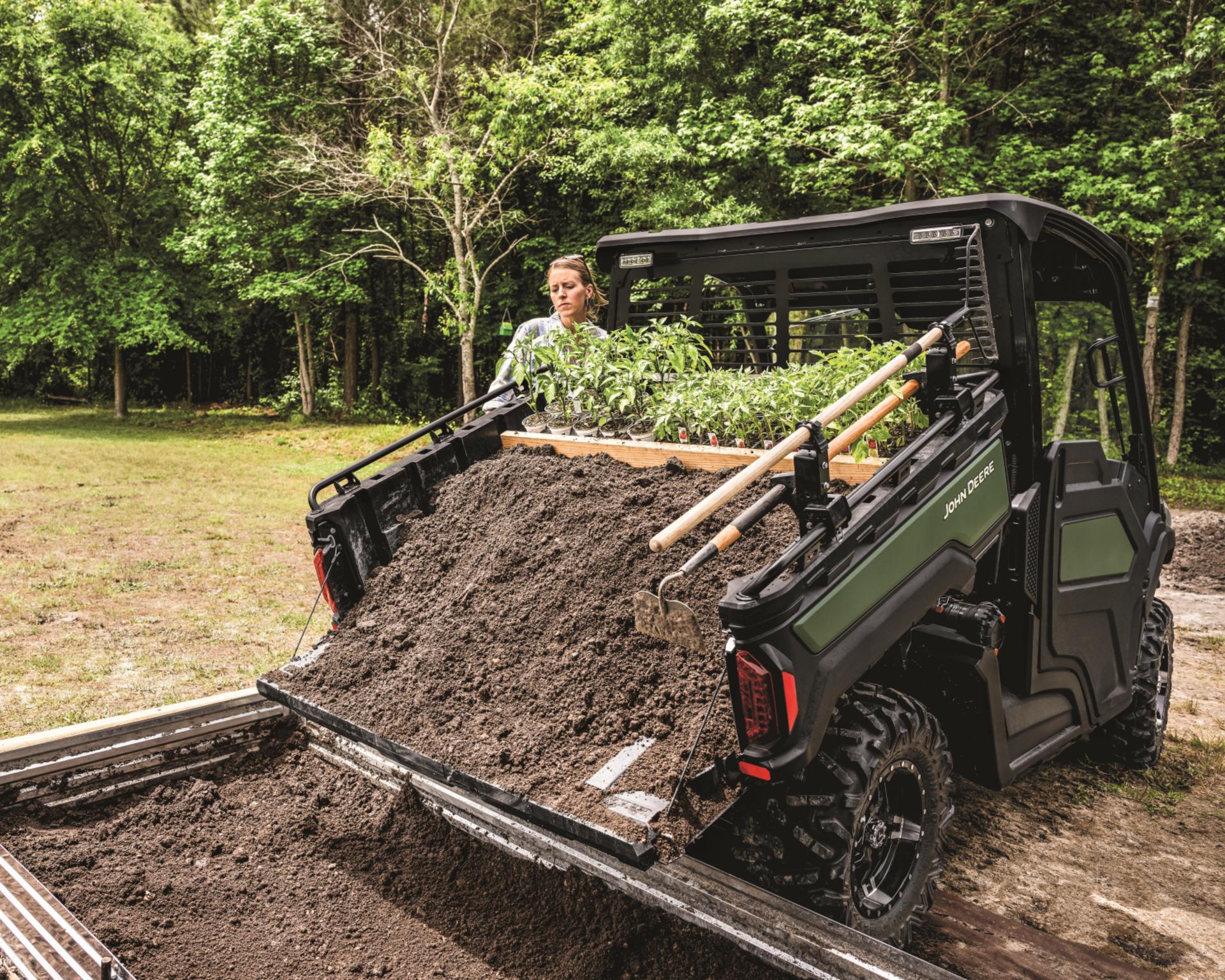 An XUV dumps soil in a garden bed.