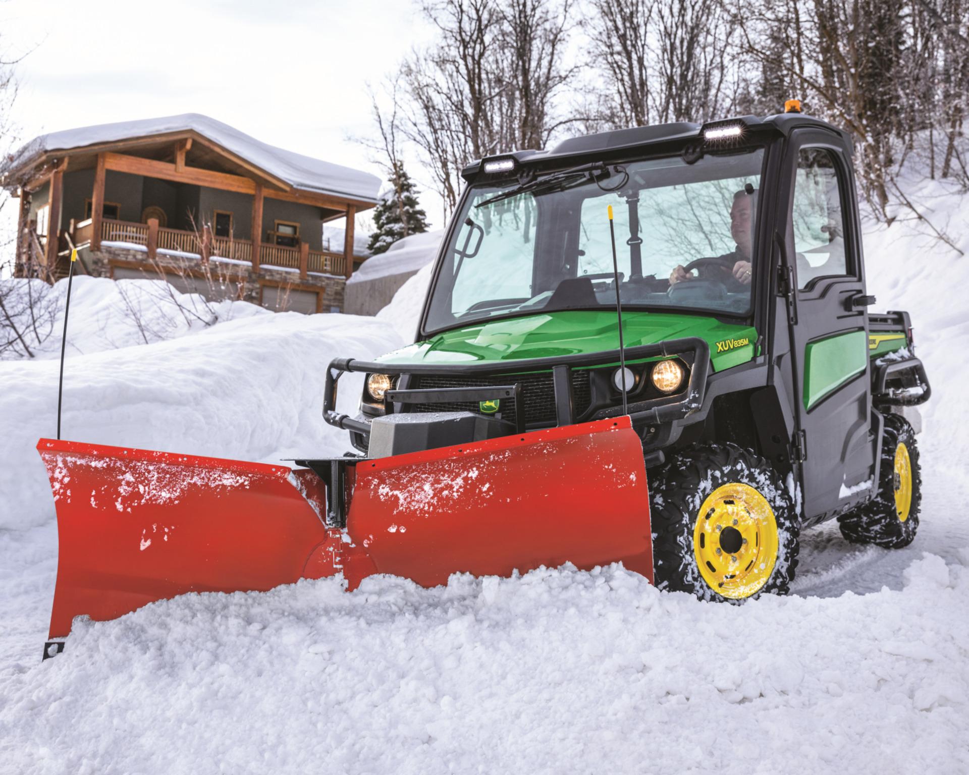 A Gator with a snow plow removes snow buildup on a property during the winter.