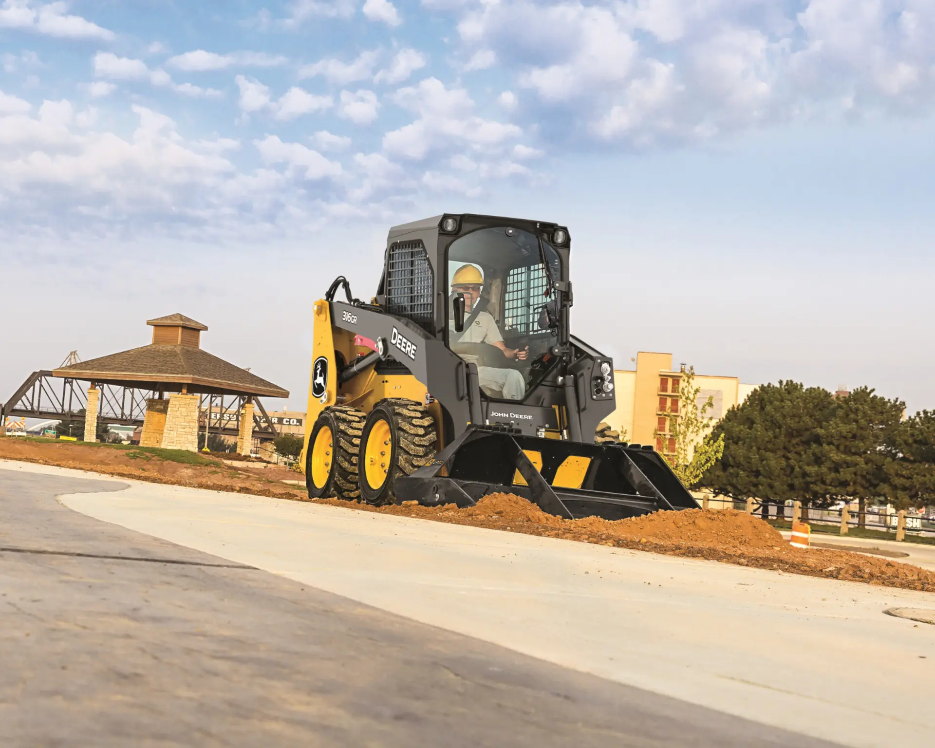 A John Deere 316GR skid steer with a front bucket attachment does work at a park.
