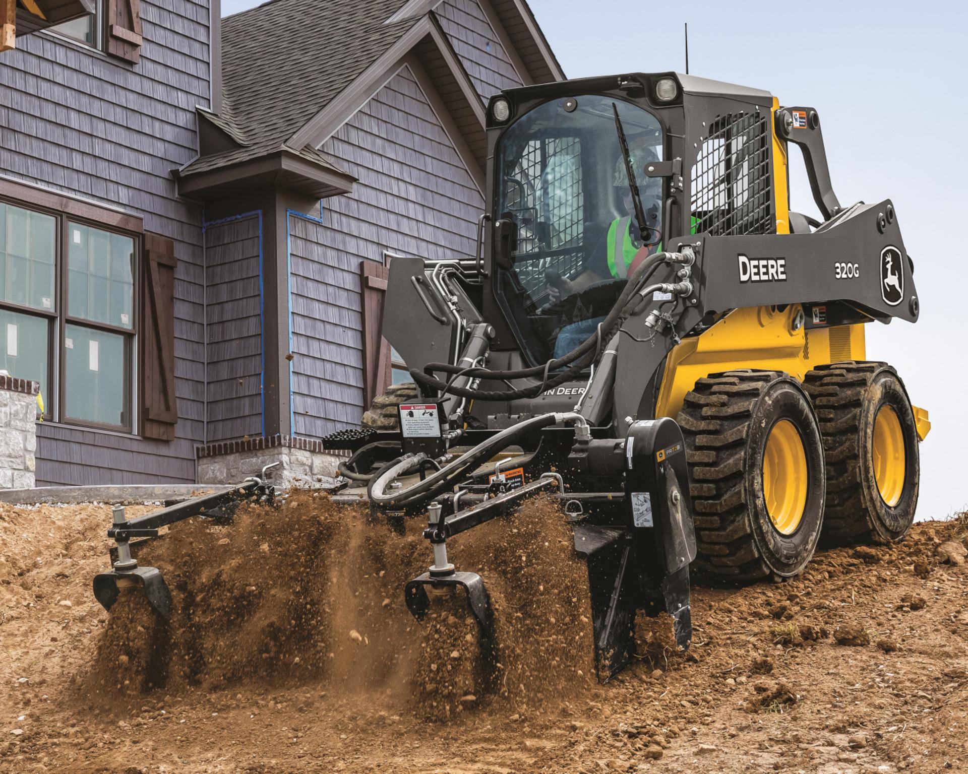 A John Deere 320G skid steer on a work site.