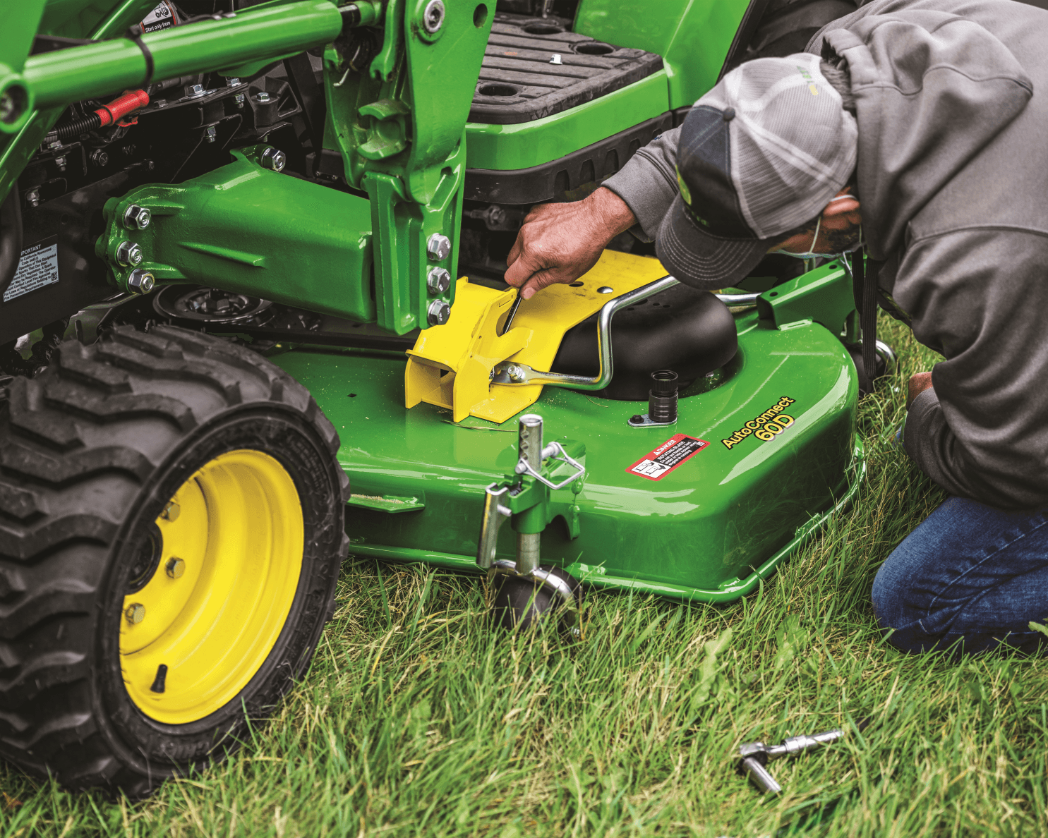 A technician changes the mower deck on a John Deere zero-turn mower.