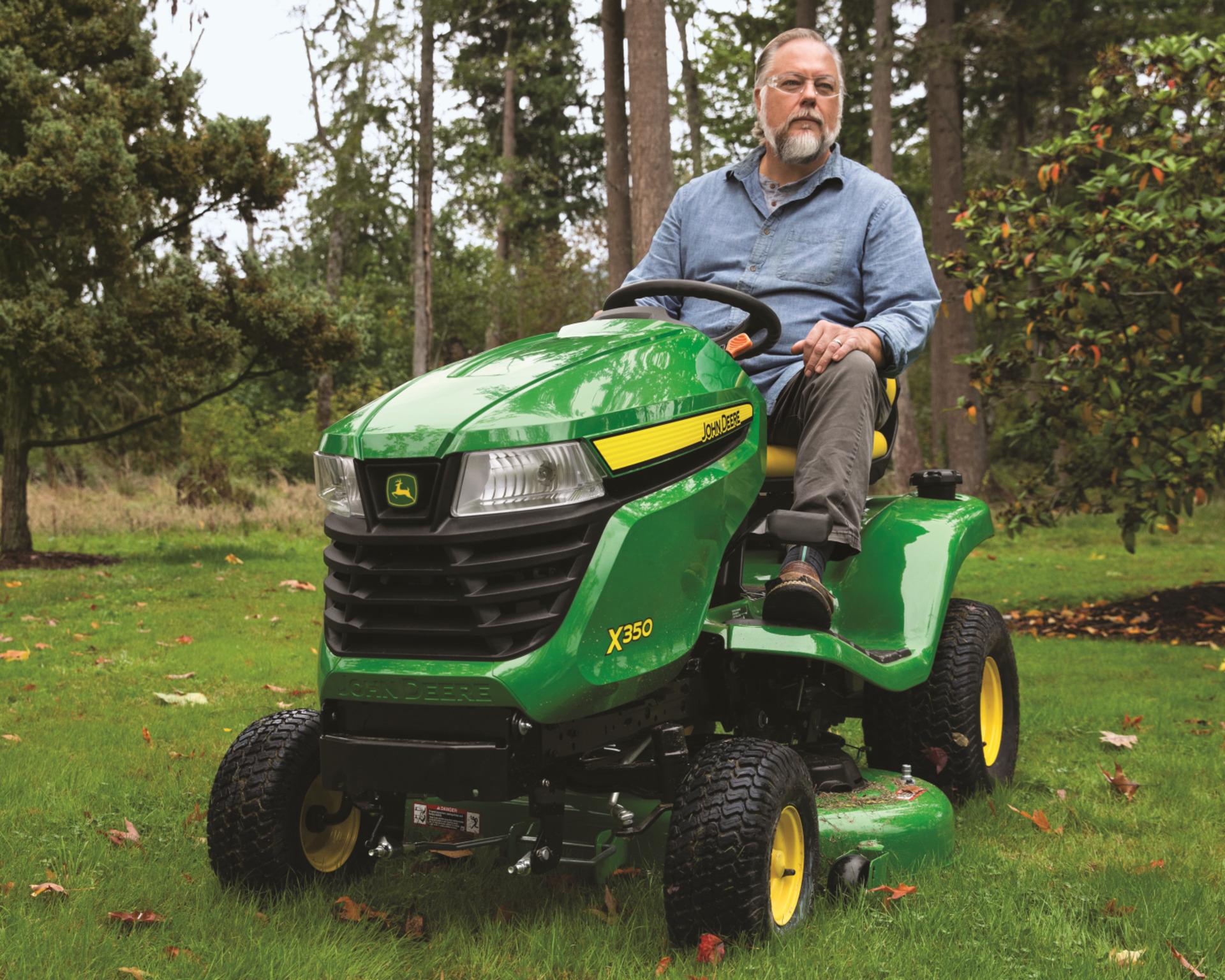 A homeowner uses a John Deere X350 to mow their lawn.