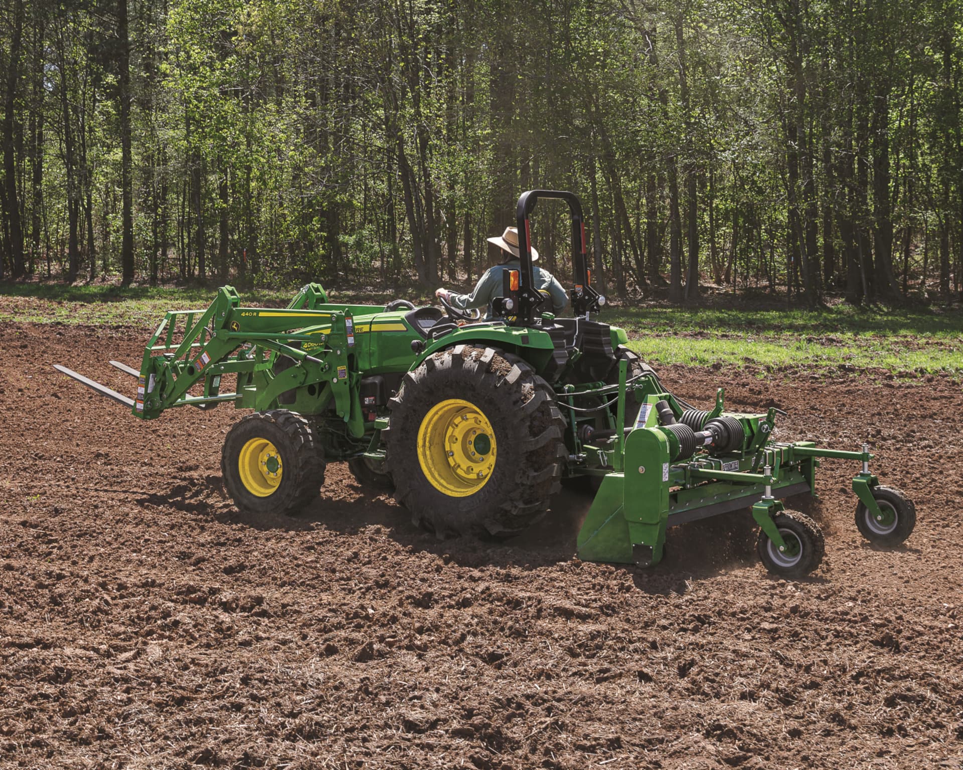 A land owner with a John Deere 4066M uses a tiling attachment to prepare land for planting season.