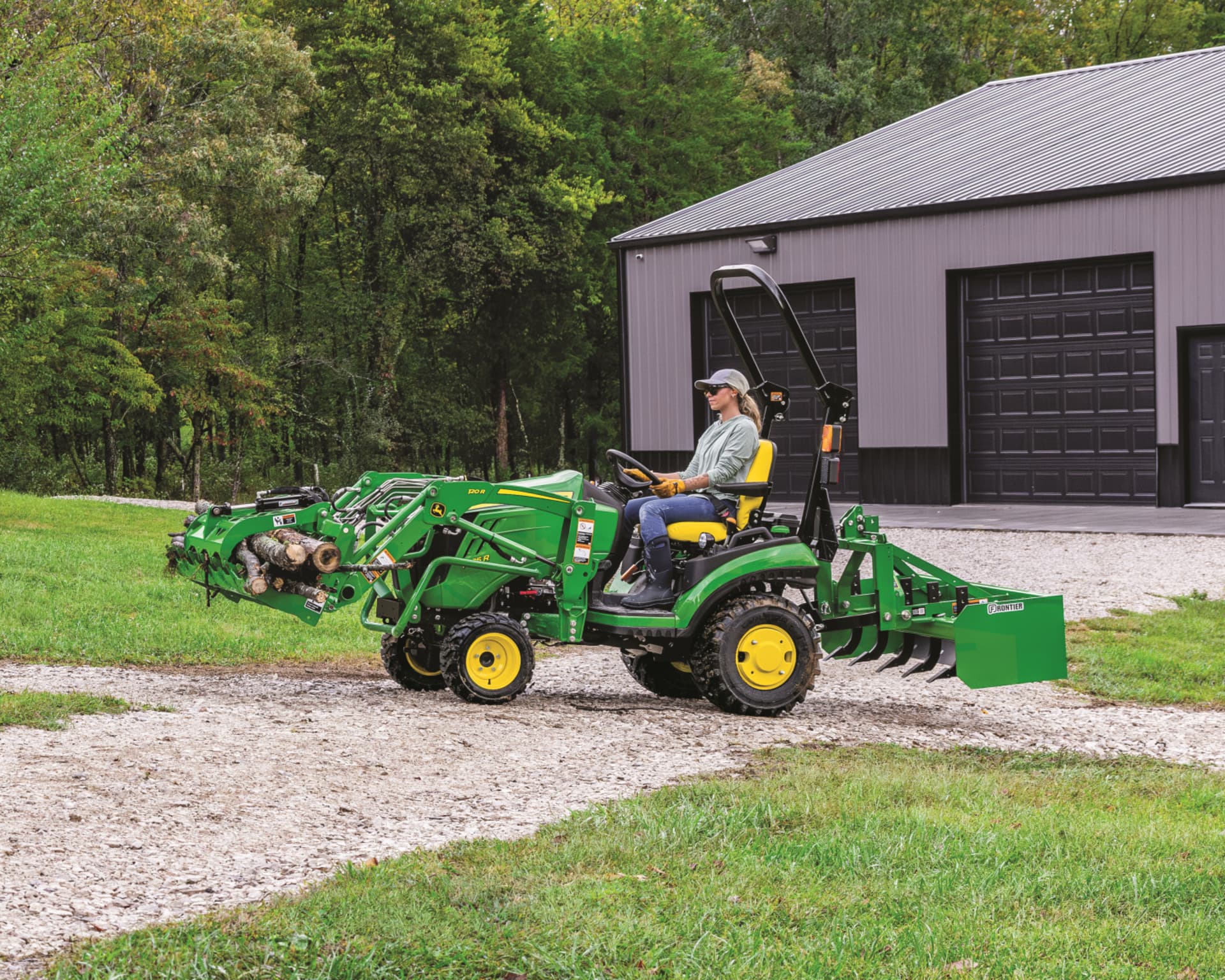 A John Deere tractor with a grapple attachment hauls wood.