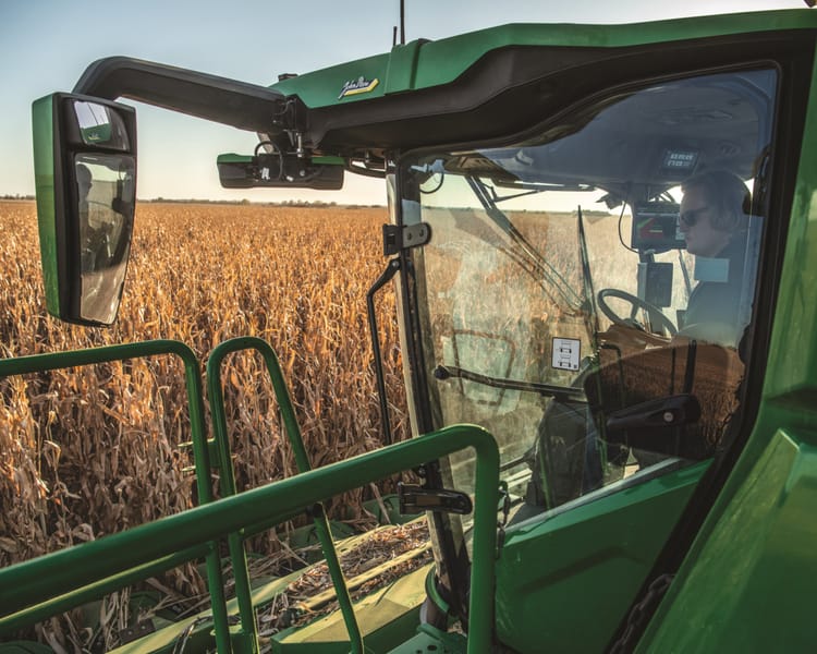 A combine moves through a corn field during fall harvest time.