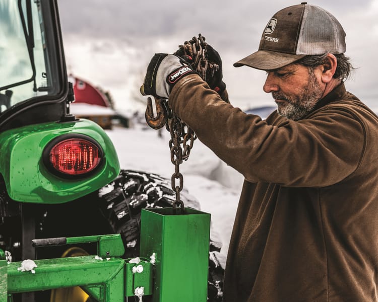 A man works on a tractor in the winter.