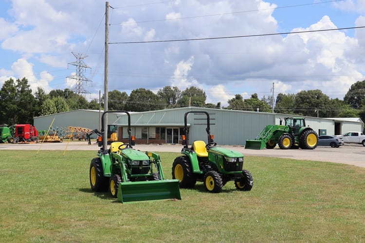 Two John Deere tractors sit in front of a Tennessee Tractor building.