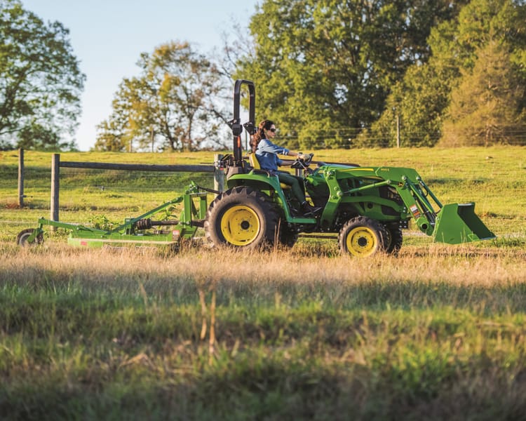 A property owner uses a rotary cutter to clear brush from a fence line.