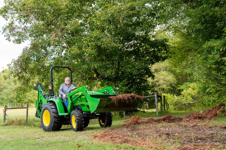 A property owners operate a compact tractor with a front-end loader to prepare their food plot for hunting season.