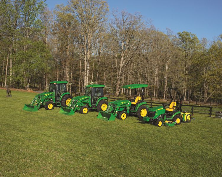 A selection of compact utility tractor models with attachments on a property.