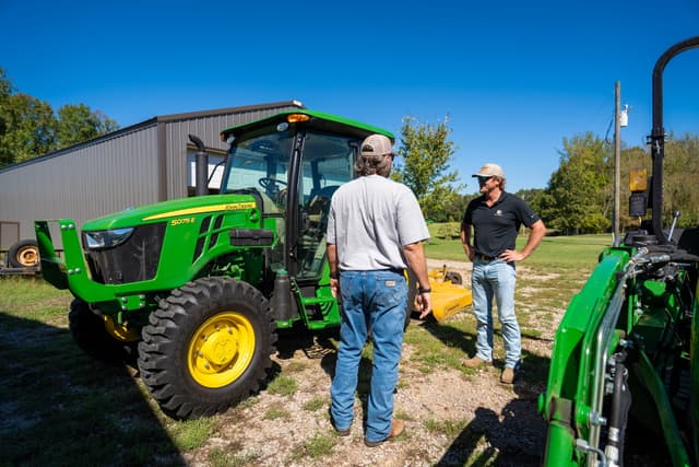 TNTR 5 series 1 Two farm workers talk on the farm standing next to a John Deere 5 Series tractor.