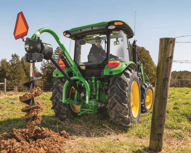TNTR post hole digger 1 A farm owner uses a post-hole digger attachment to dig a fence post hole.