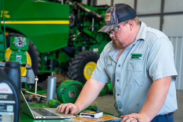 DSC09490 (1) A Tennessee Tractor equipment specialist inspects a John Deere machine in the shop.