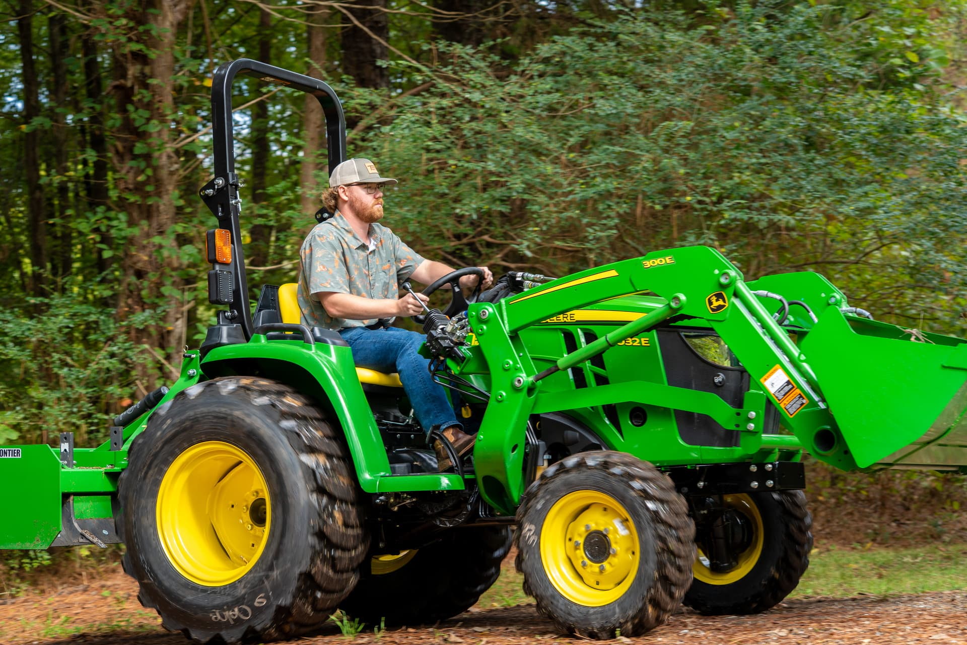 A property owner operates a John Deere 3 Series compact tractor.