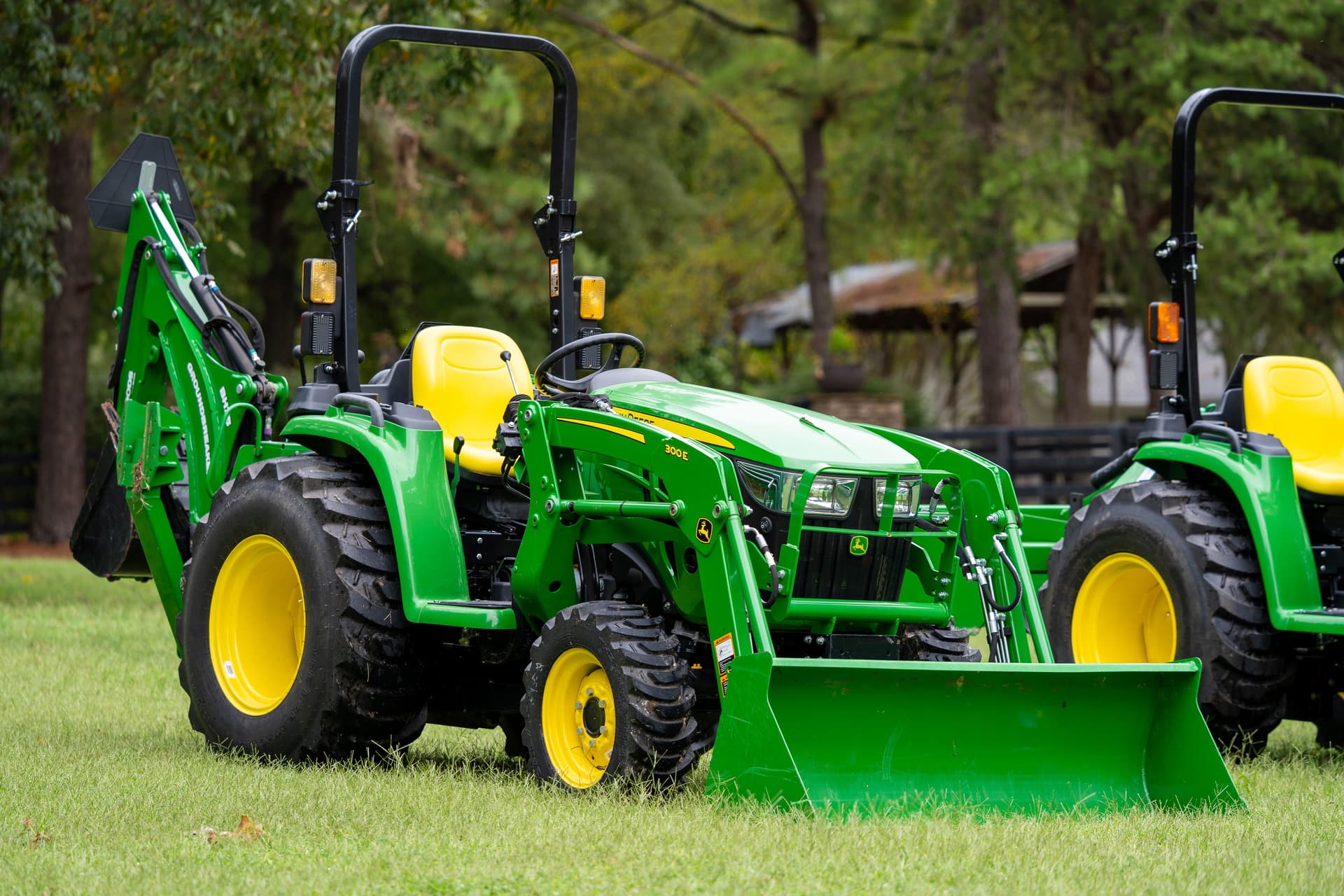 A compact tractor with front-end loader and excavator attachments.