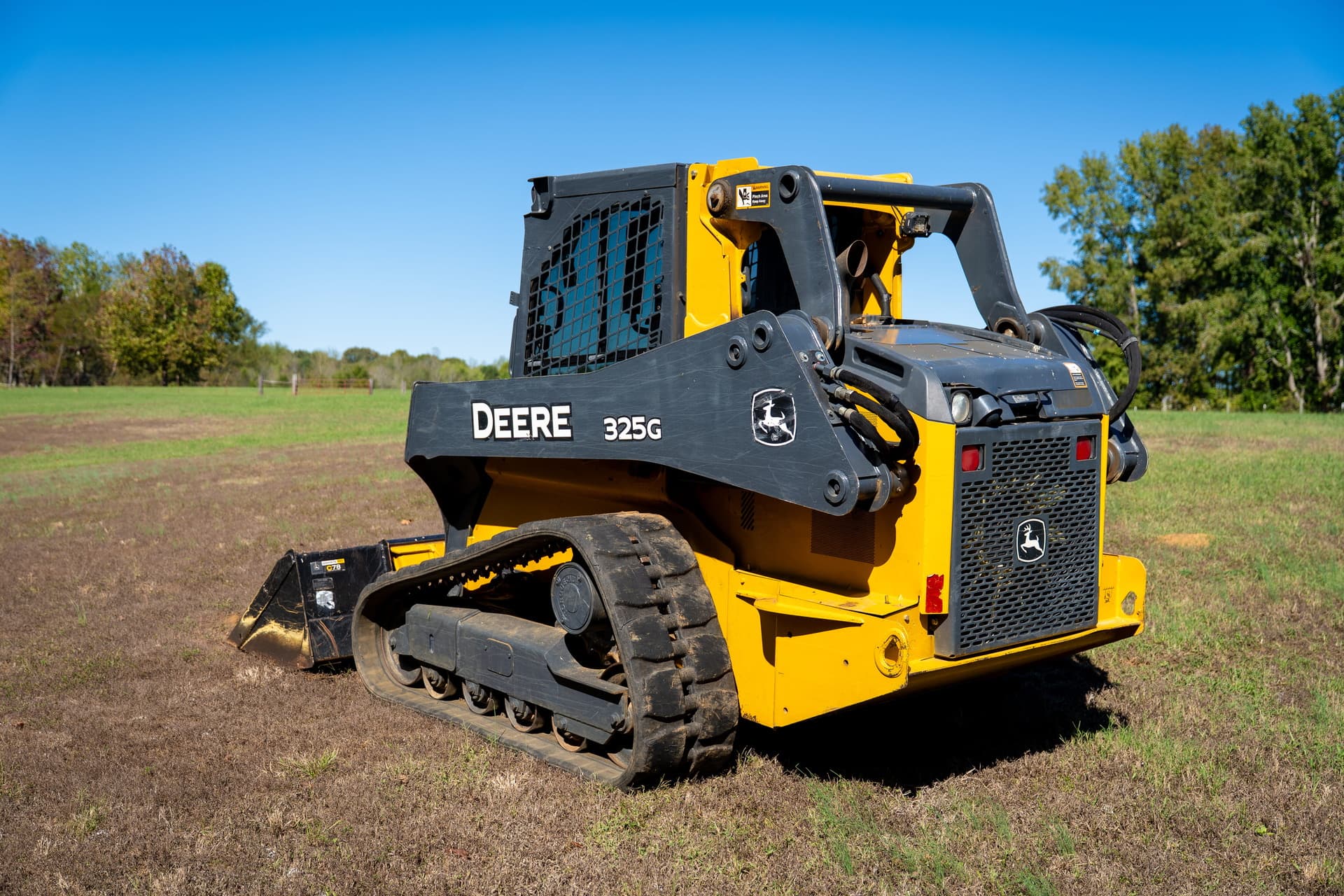 A compact track loader sits on a property prepared to help with a water well site.