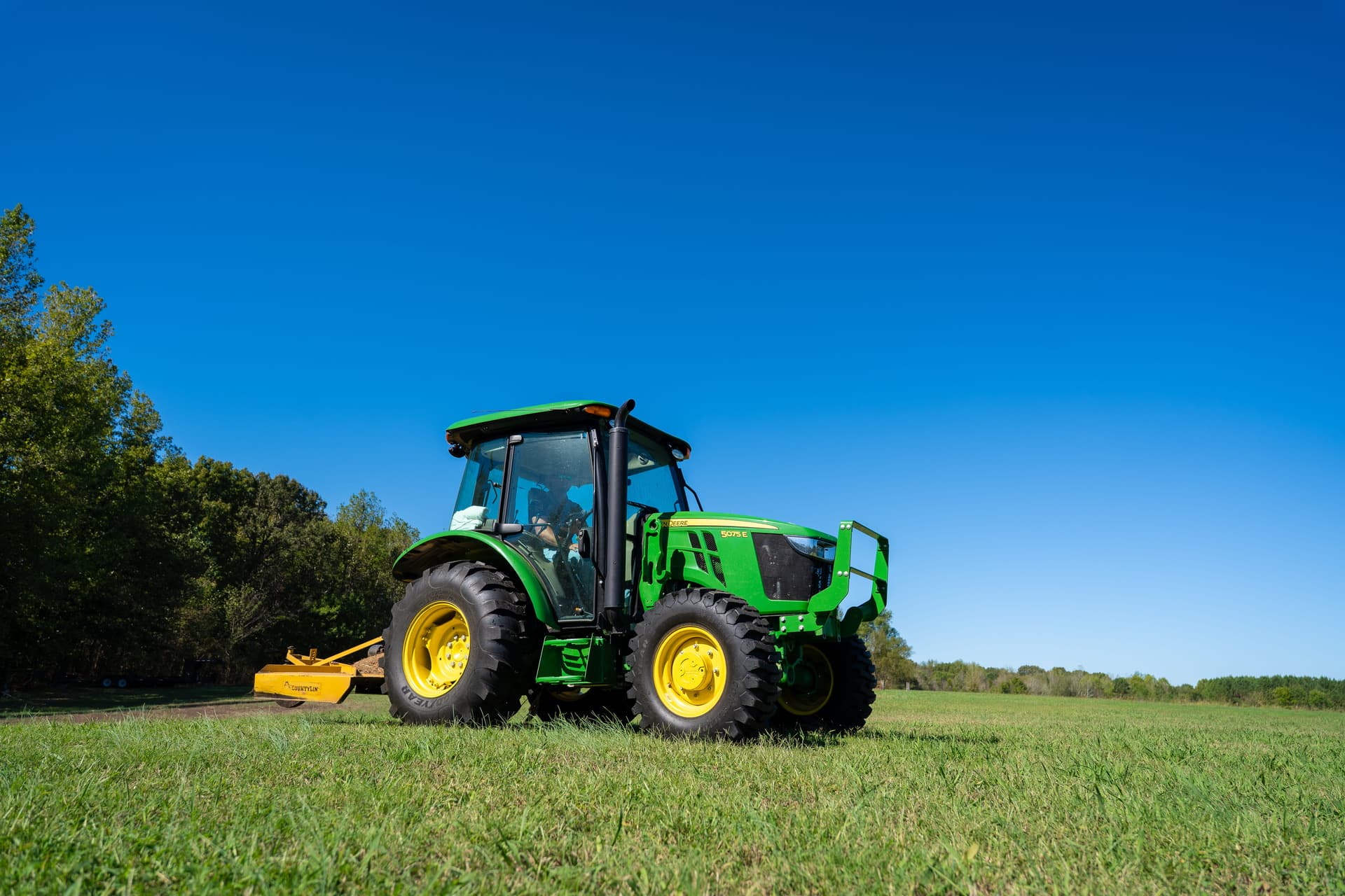A John Deere 5 Series tractor uses a rotary cutter attachment on a property in Tennessee.