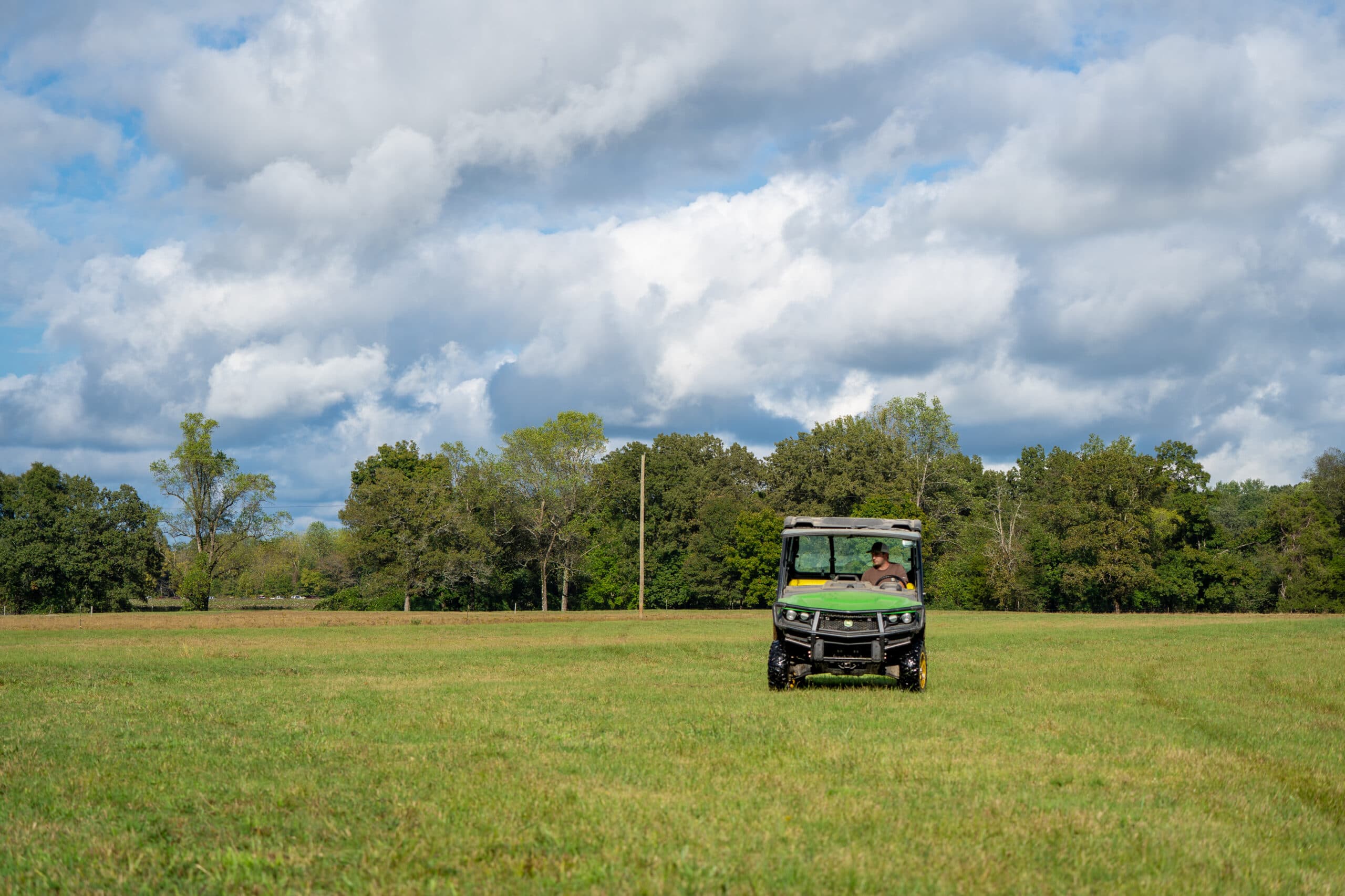 A John Deere Gator UTV operated by a property owner in a field in rural Tennessee.