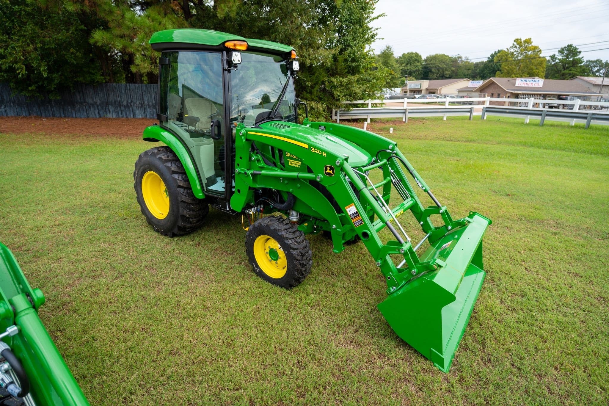A John Deere 3 Series tractor with an enclosed cab and front-end loader attachment.