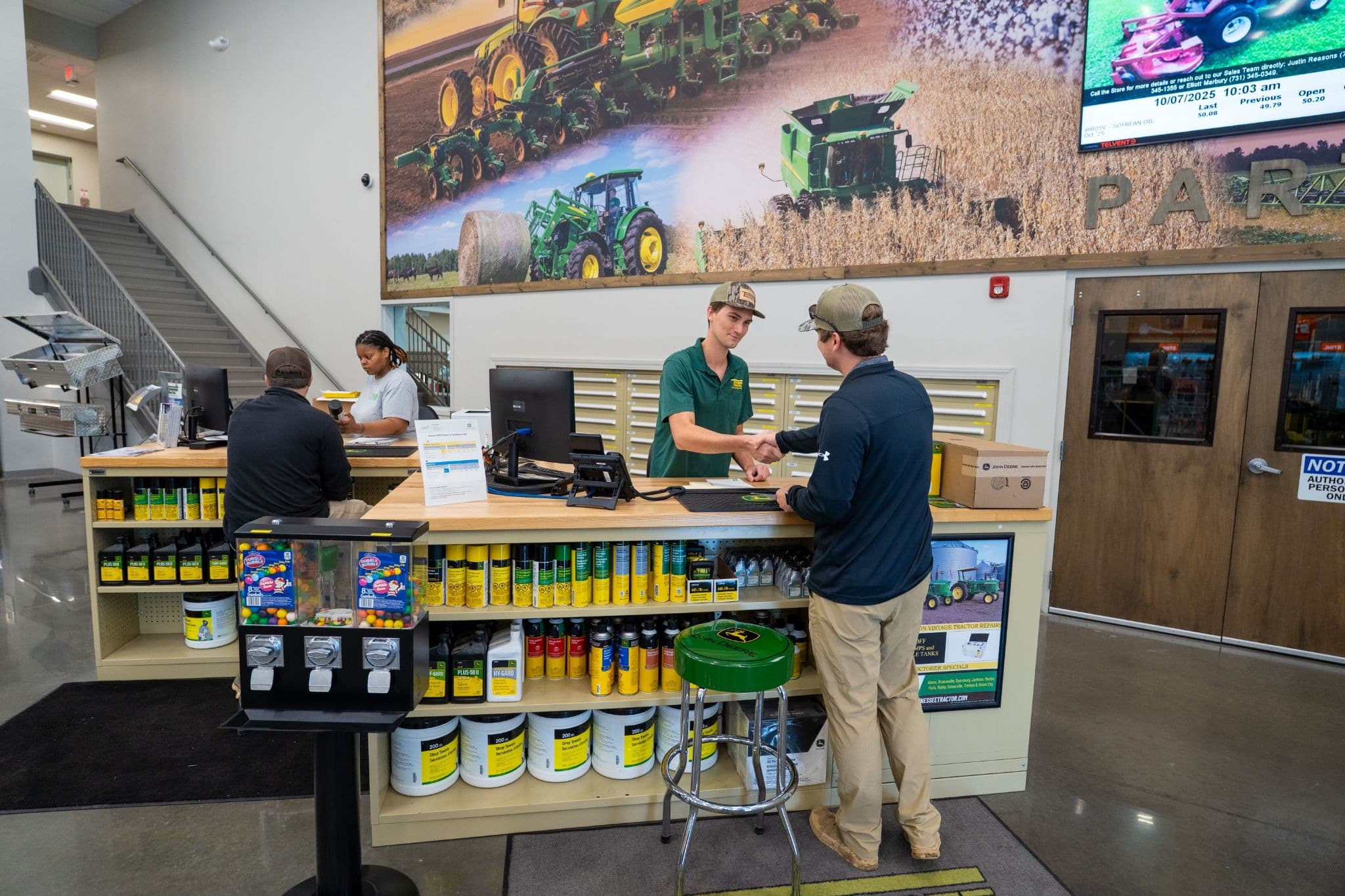 A Tennessee Tractor parts specialist shakes hands with a customer at the parts counter.