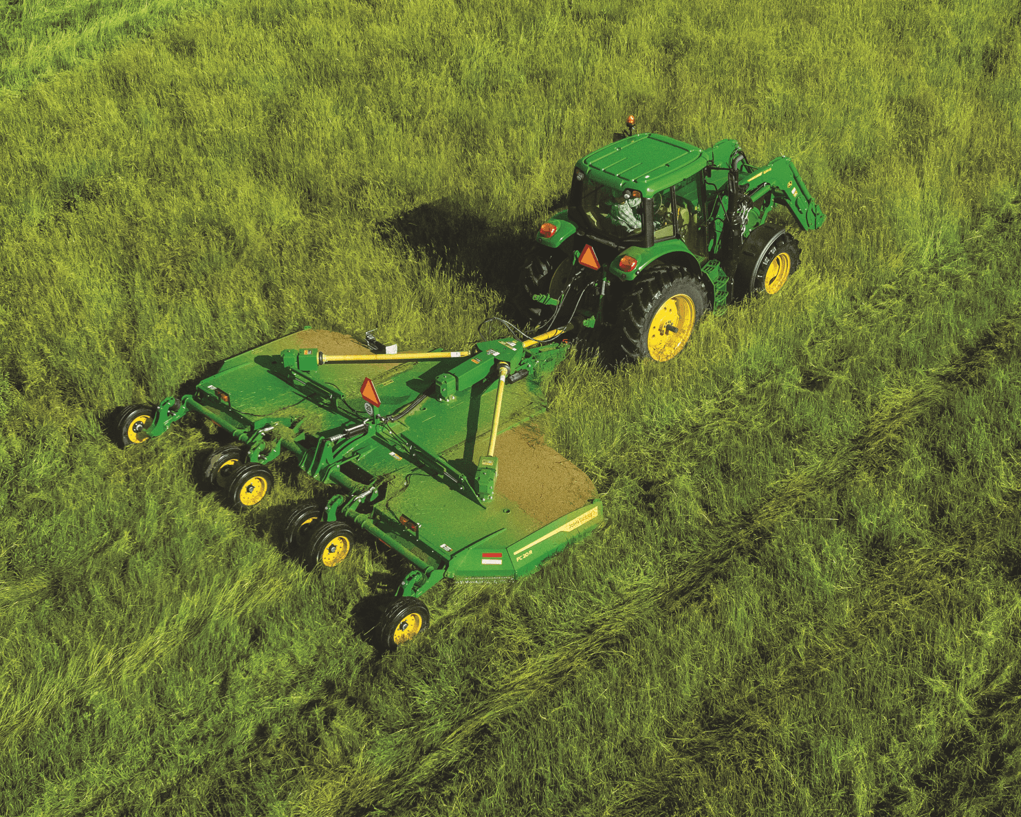 A John Deere tractor uses a rotary cutter attachment to clear a grassy area in Tennessee.